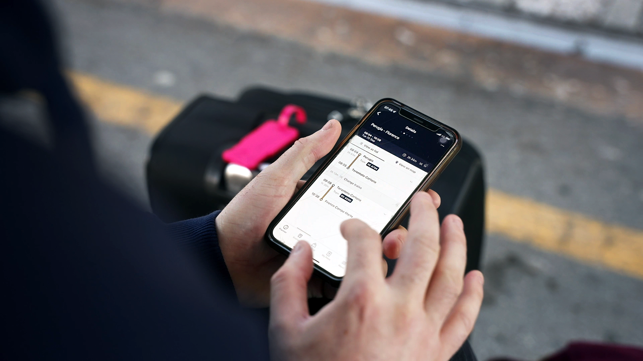A person checking train times while using the Rail Planner App on a phone.